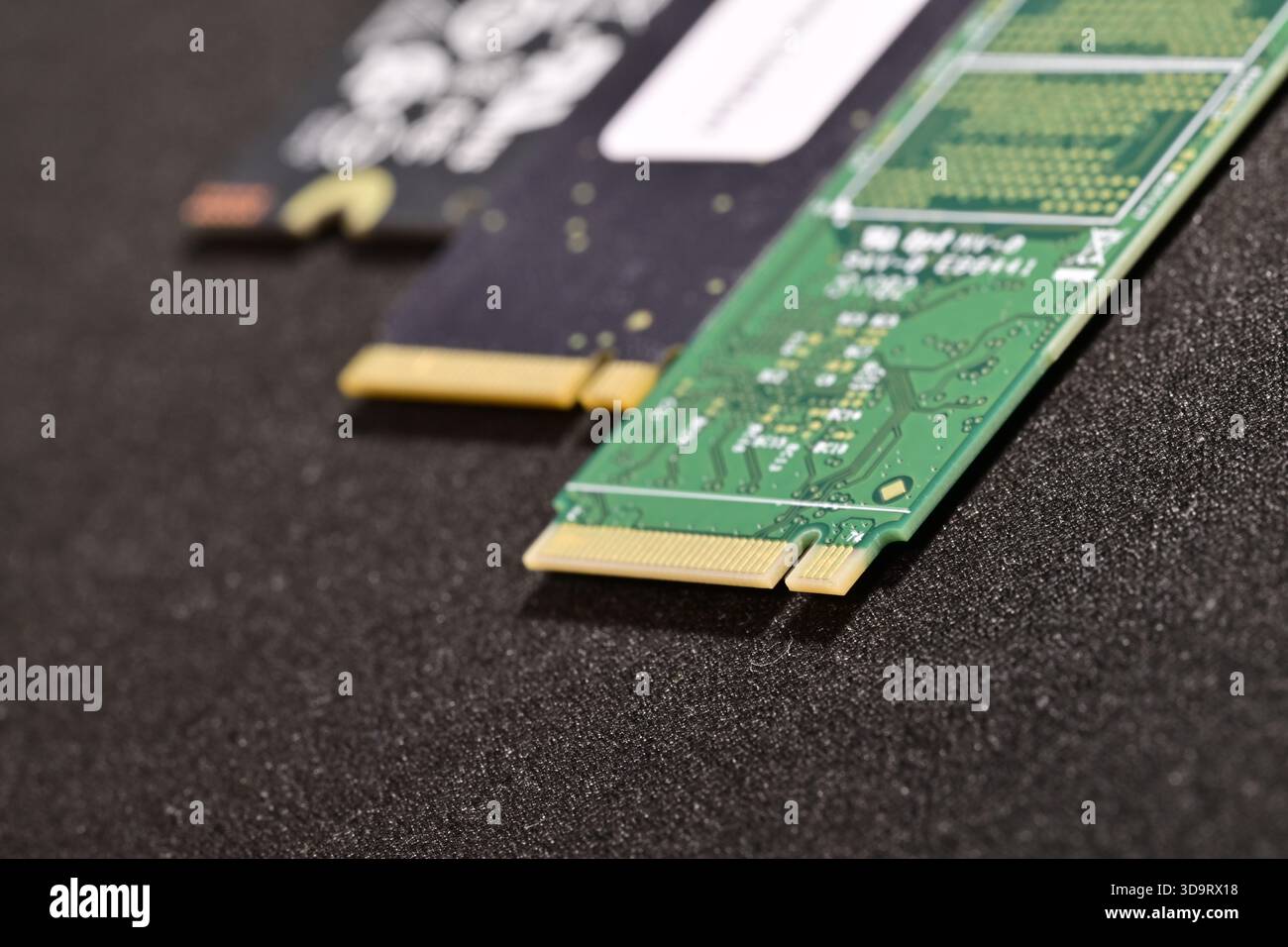 Close-up view of two computer M.2 SSD Harddrive modules on a textured black surface, showcasing their circuit designs and gold connectors. Stock Photo