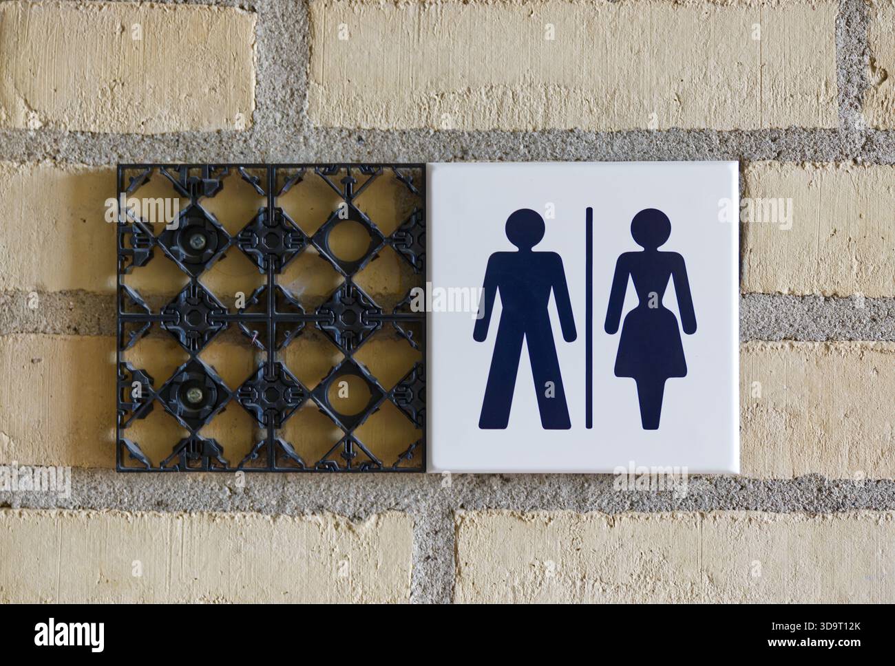 A restroom sign with male and female symbols on a textured wall. The sign with "Divers" was removed after Trump won and gender was discontinued in fav Stock Photo