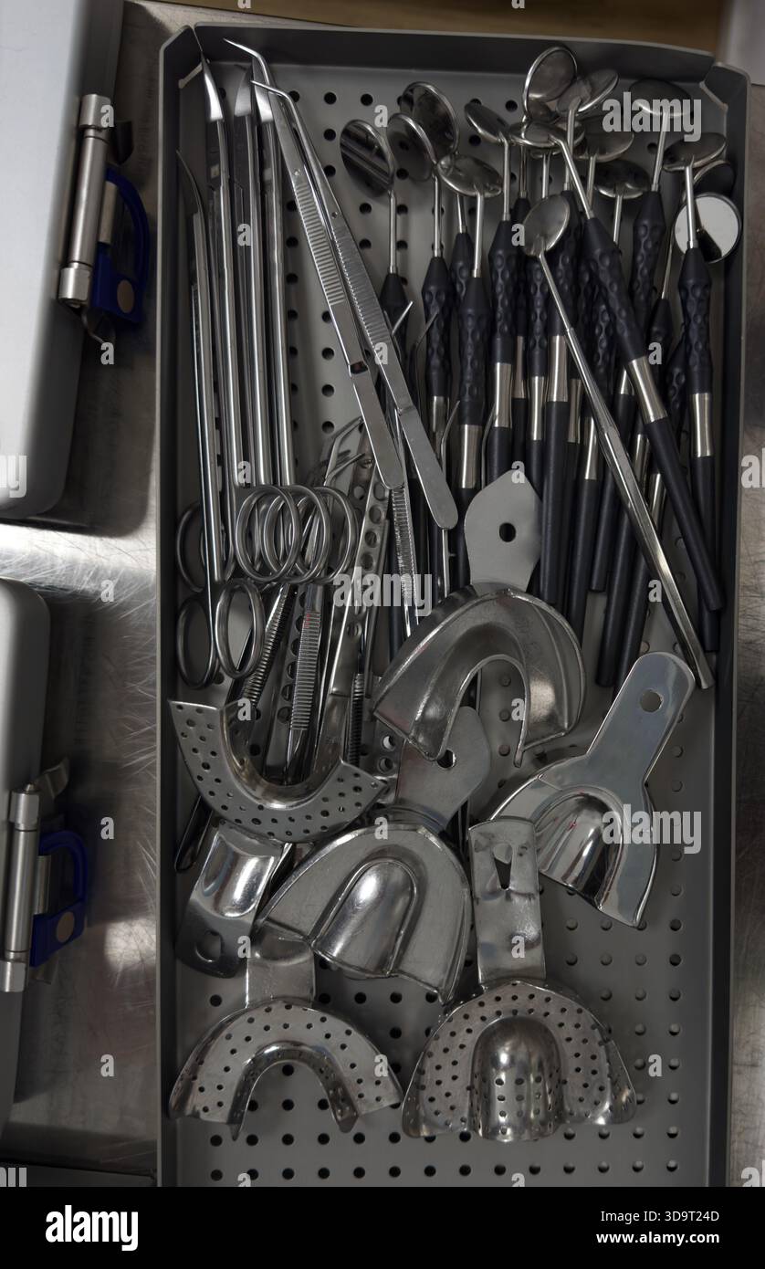 A collection of various dental instruments organized in a tray. The instruments include mirrors, explorers, forceps, and other tools used in dental pr Stock Photo