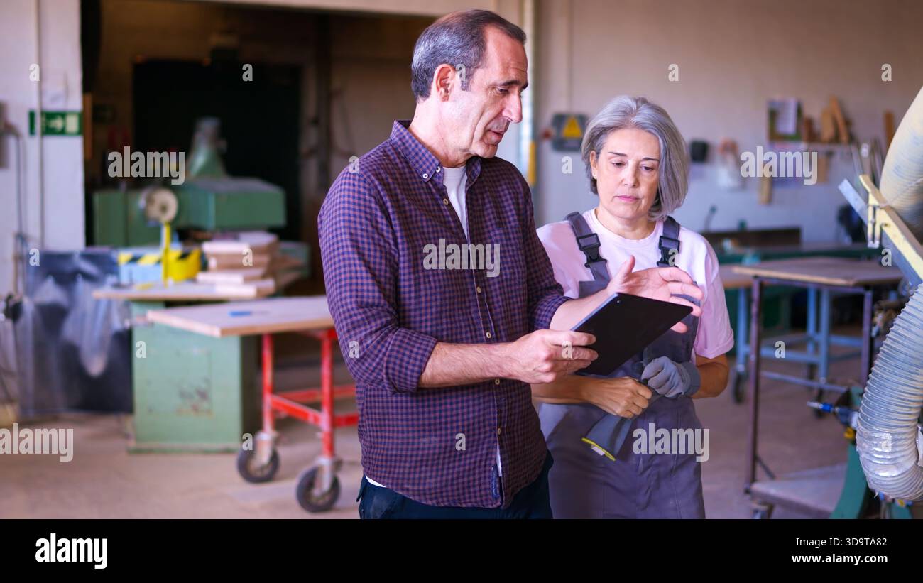 Senior carpenters discussing project using digital tablet in workshop Stock Photo