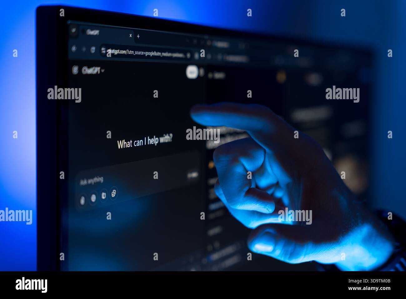 Hand pointing at ChatGPT interface on computer screen with blue light Stock Photo