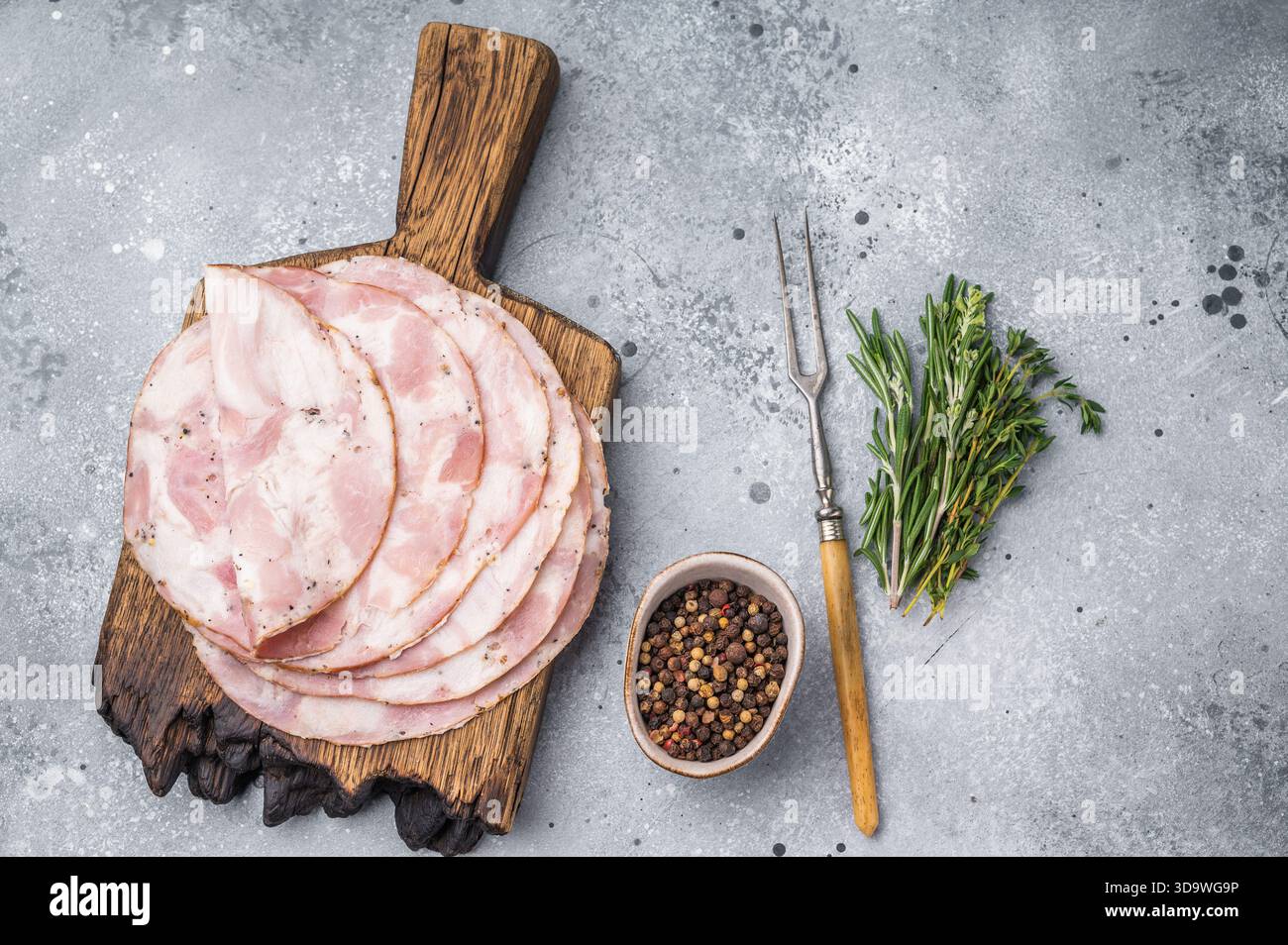 Traditional deli meat (Pancetta) and serving fork on a minimal grey background, perfect for a clean menu design Stock Photo