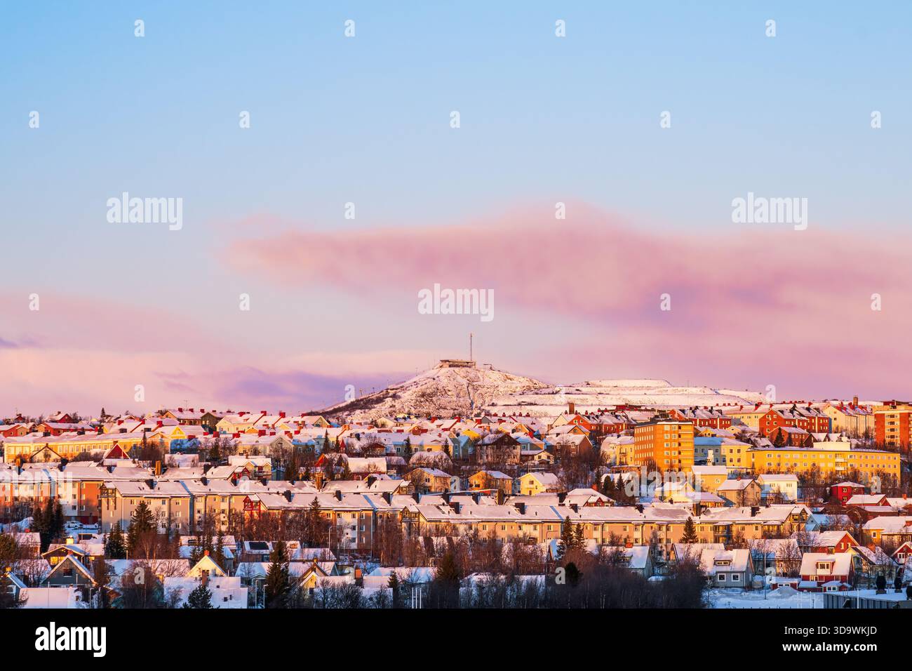Kiruna skyline, Sweden, in winter with orange and red hues from the low sun. Snow. Colorful houses. Ski slopes. Stock Photo