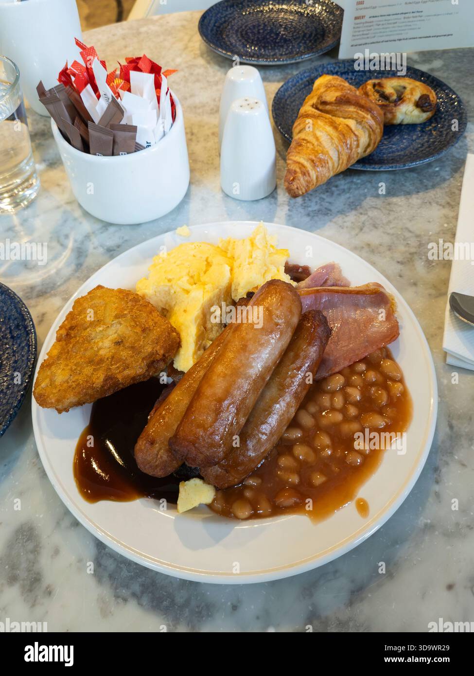 Full English breakfast being eaten by business traveller in a Belfast hotel, Northern Ireland, with scrambled egg, sausages, bacon, beans, hash browns - Smartphone Captured Stock Image