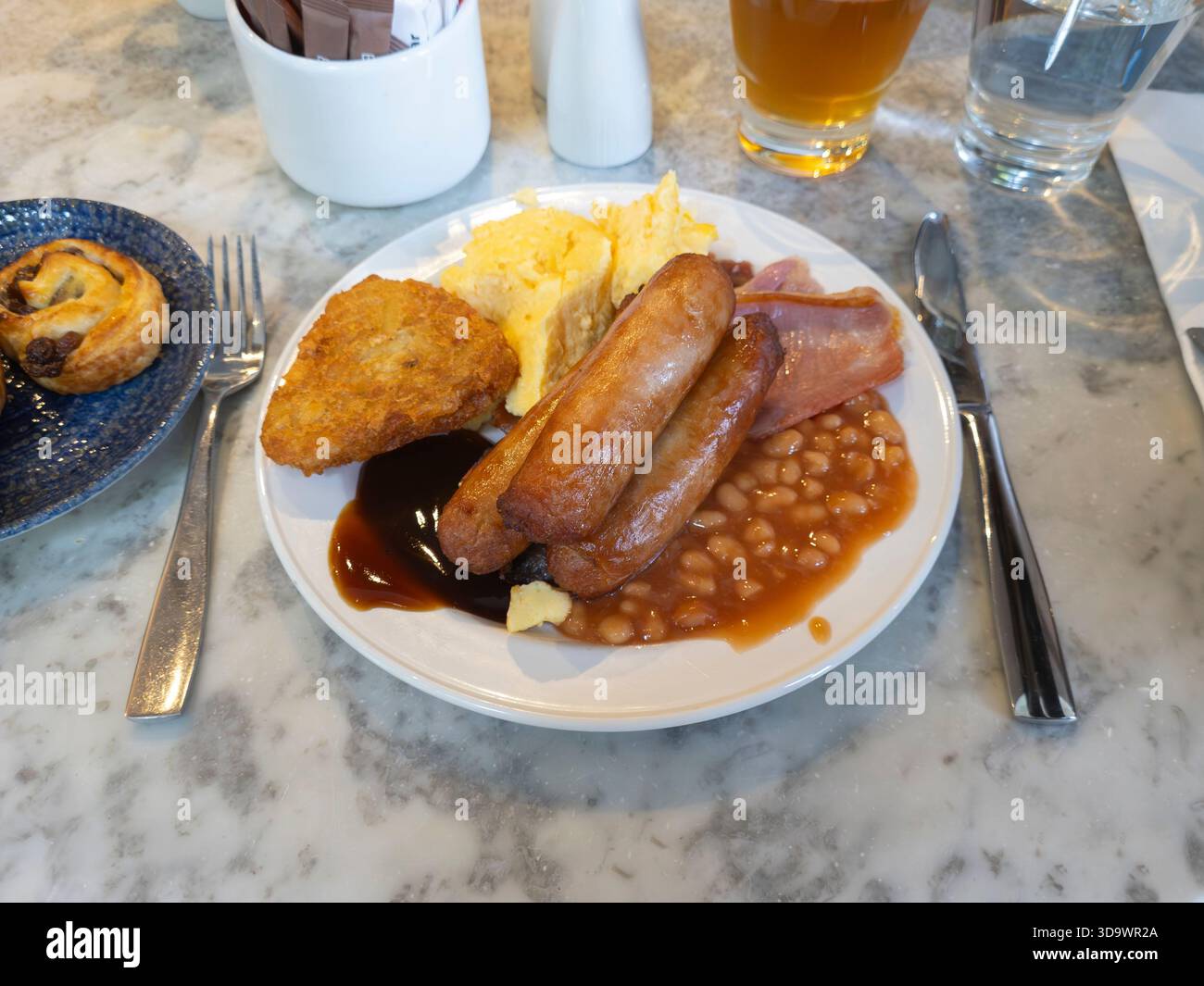 Full English breakfast being eaten by business traveller in a Belfast hotel, Northern Ireland, with scrambled egg, sausages, bacon, beans, hash browns - Smartphone Captured Stock Image