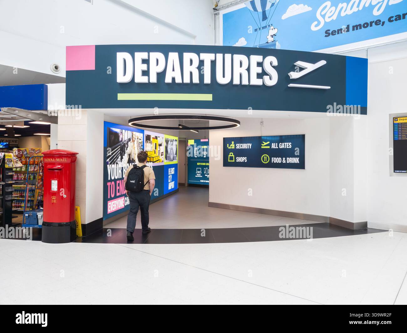 A man walking through the entrance to flight departures at Belfast International Airport, Northern Ireland. Concept: VINCI Airports, frequent flier - Smartphone Captured Stock Image