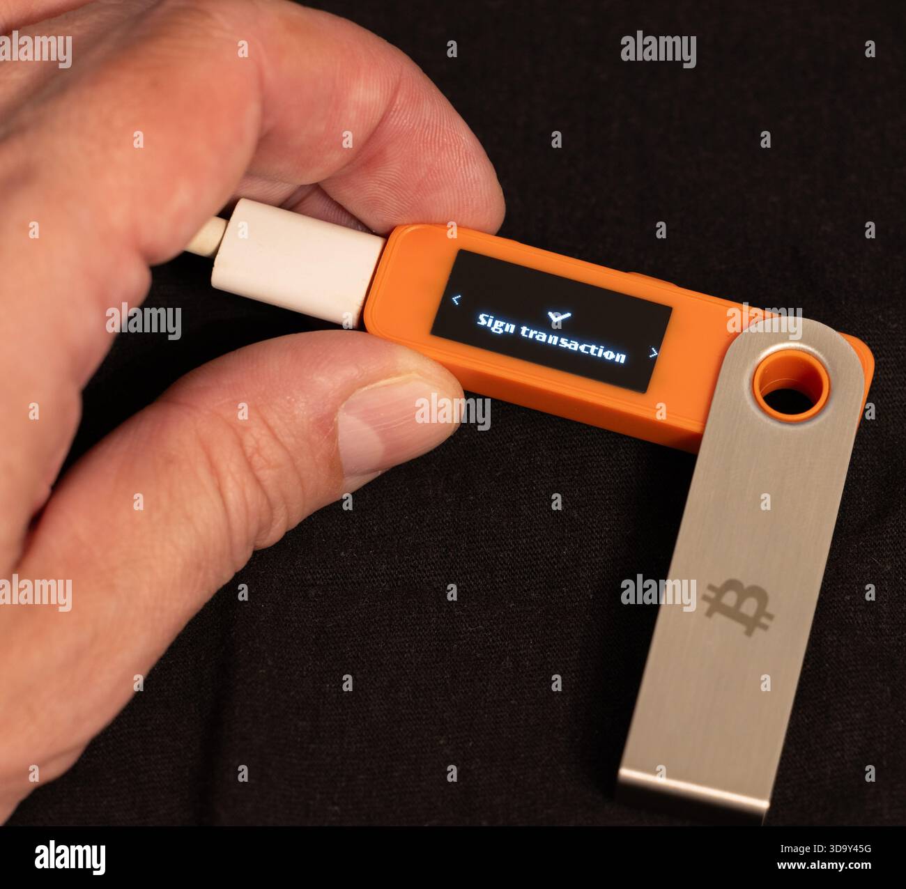 Sign transaction message on hardware Bitcoin wallet in hands Stock Photo