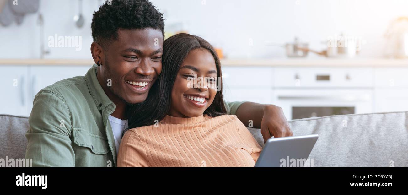 Couple Enjoying Time Together While Using a Tablet in a Bright Kitchen Setting Stock Photo