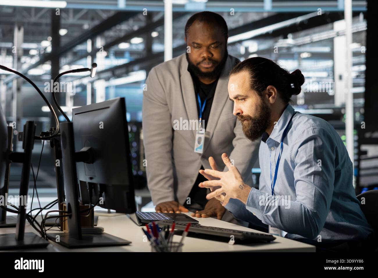 Technicians in data center office using computer, verifying firewall configurations. Teamworking IT specialists performing equipment vulnerability scans in server hub using PC Stock Photo