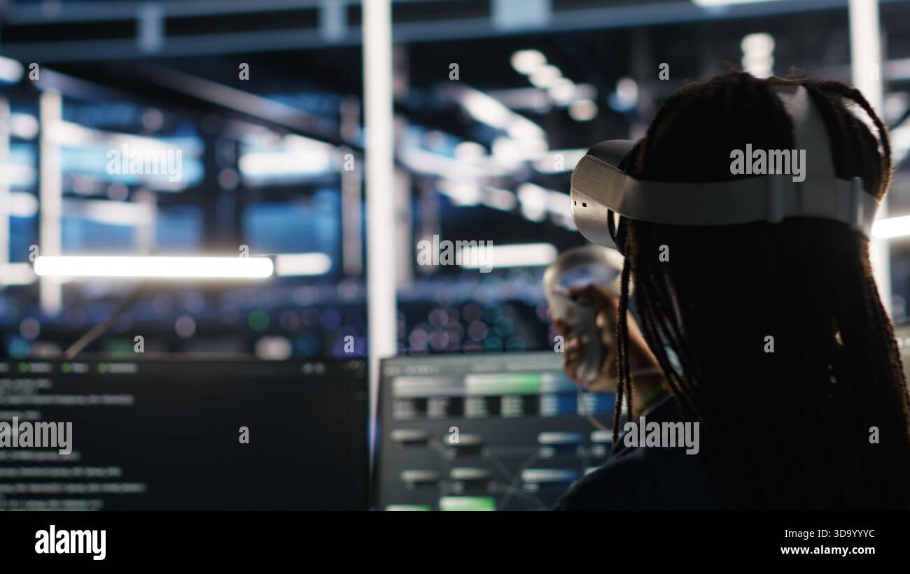 Server farm admin using VR equipment and node tree systems to categorize unstructured data. Data center IT specialist uses virtual reality headset and visual programming software, camera B Stock Photo