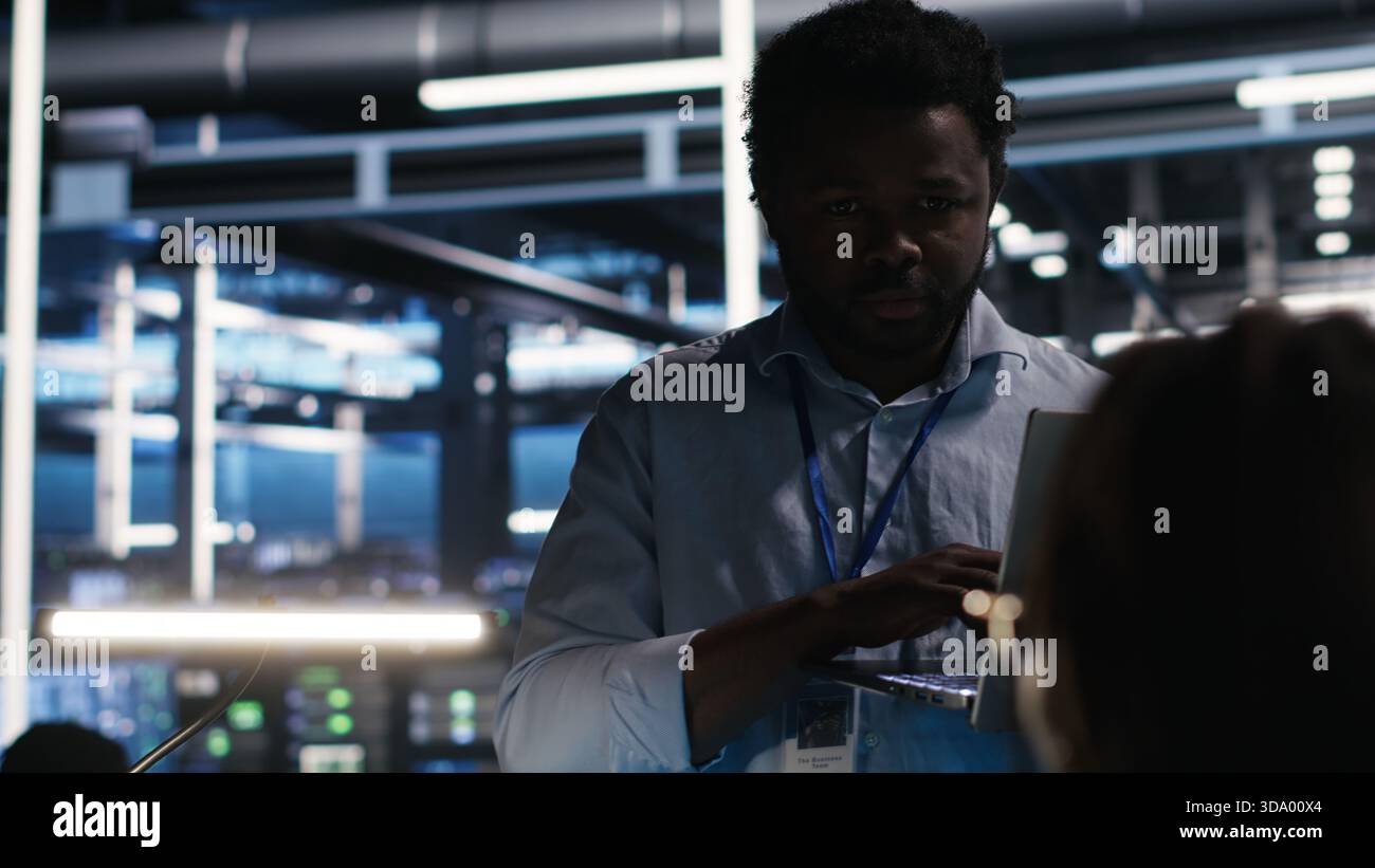 Server farm manager supervising engineer using node tree systems to categorize unstructured data. Data center supervisor overseeing IT expert using natural language processing software, camera B Stock Photo