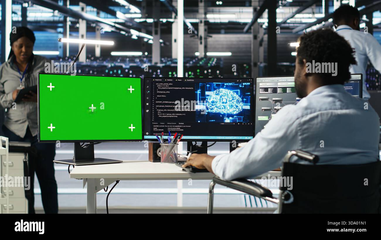 Data center worker with paraplegia using green screen PC to apply node tree programming. Server hub admin with disability uses visual programming on mockup computer to identify data patterns, camera B Stock Photo