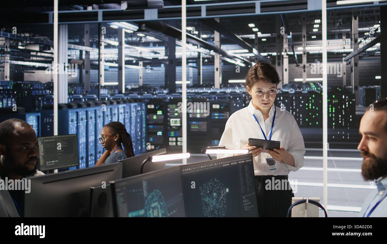 Server hub supervisor overseeing data scientist examining neural network algorithm on screen. Manager reviewing performance dashboards in artificial intelligence infrastructure environment, camera A Stock Photo