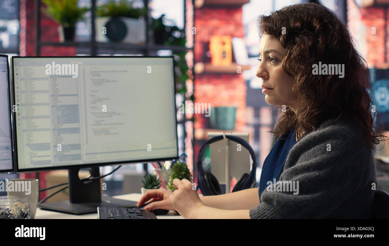 Female programmer developing app and software algorithm on pc, working at creative agency. Engineer uses digital tools and focuses on java script engineering and coding, IT specialist. Camera B. Stock Photo
