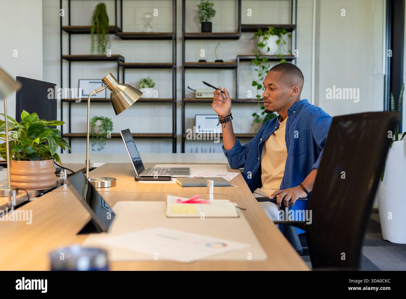 African American man writing with pen and working on laptop at office desk, copy space Stock Photo