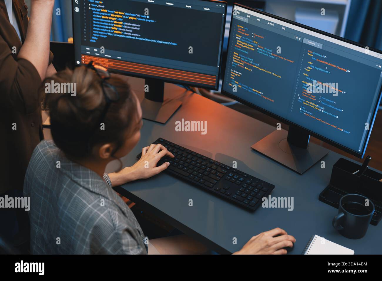 IT developers discussing with point to intelligent website development coder system running data online on pc of two screens with information Stock Photo