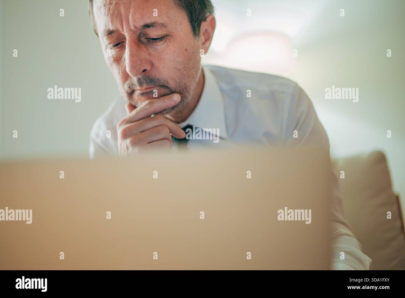 Thoughtful professional analyzing information on a laptop, focusing on strategy and decision-making. Selective focus, Stock Photo