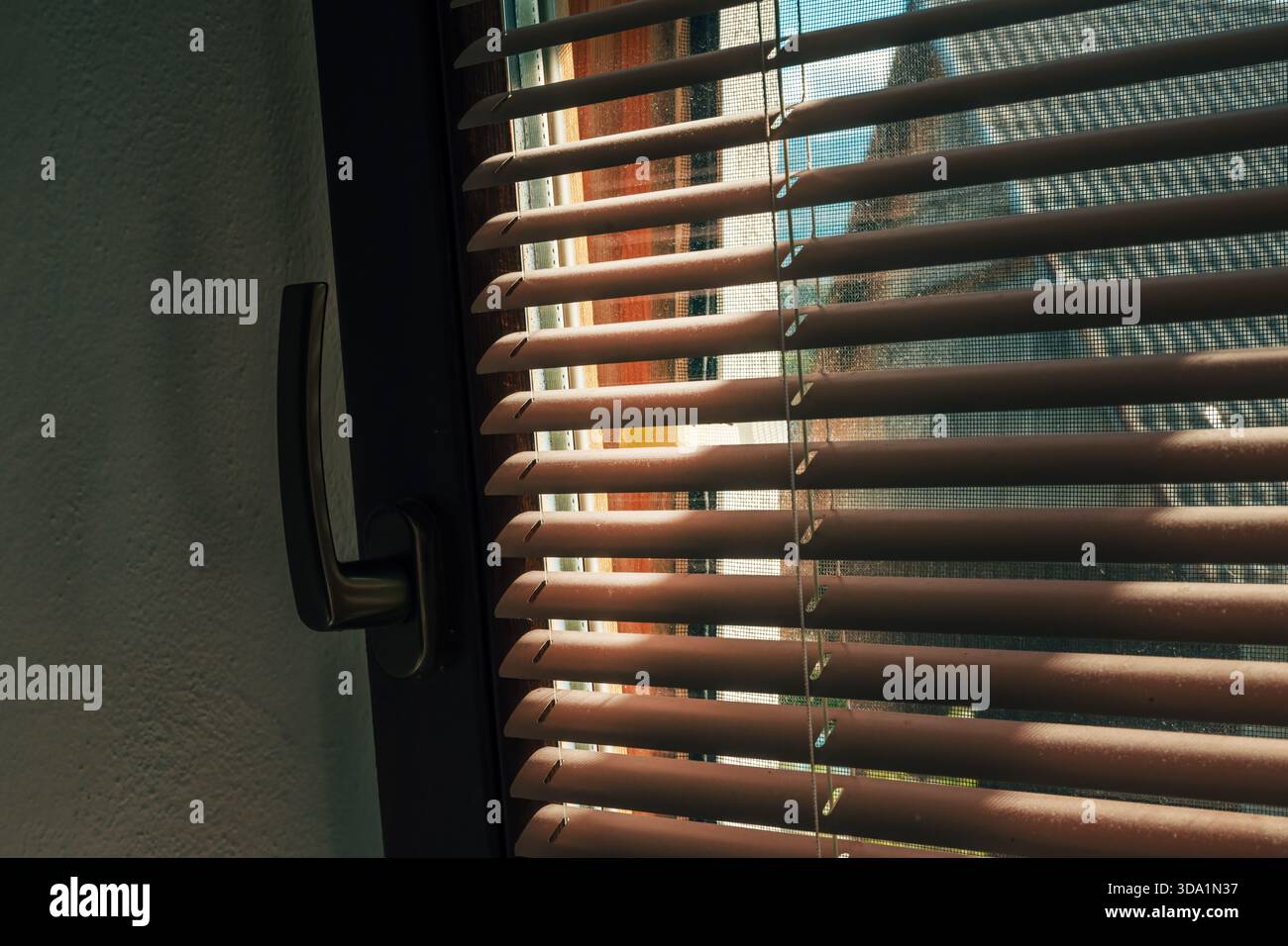 Sunlight streaming through window blinds, casting striped shadow pattern indoors. Selective focus. Stock Photo