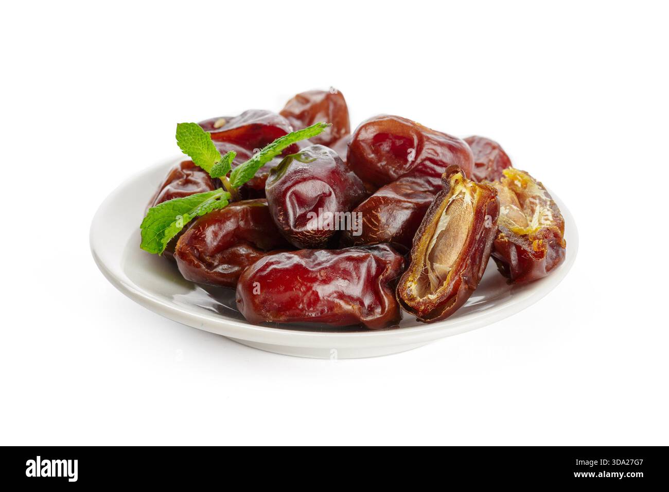 Delicious fresh dates served on a white plate with mint leaves for decoration Stock Photo