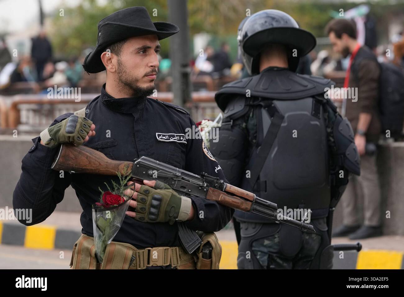 A Syrian police officer with a flower stands guard during a parade ...