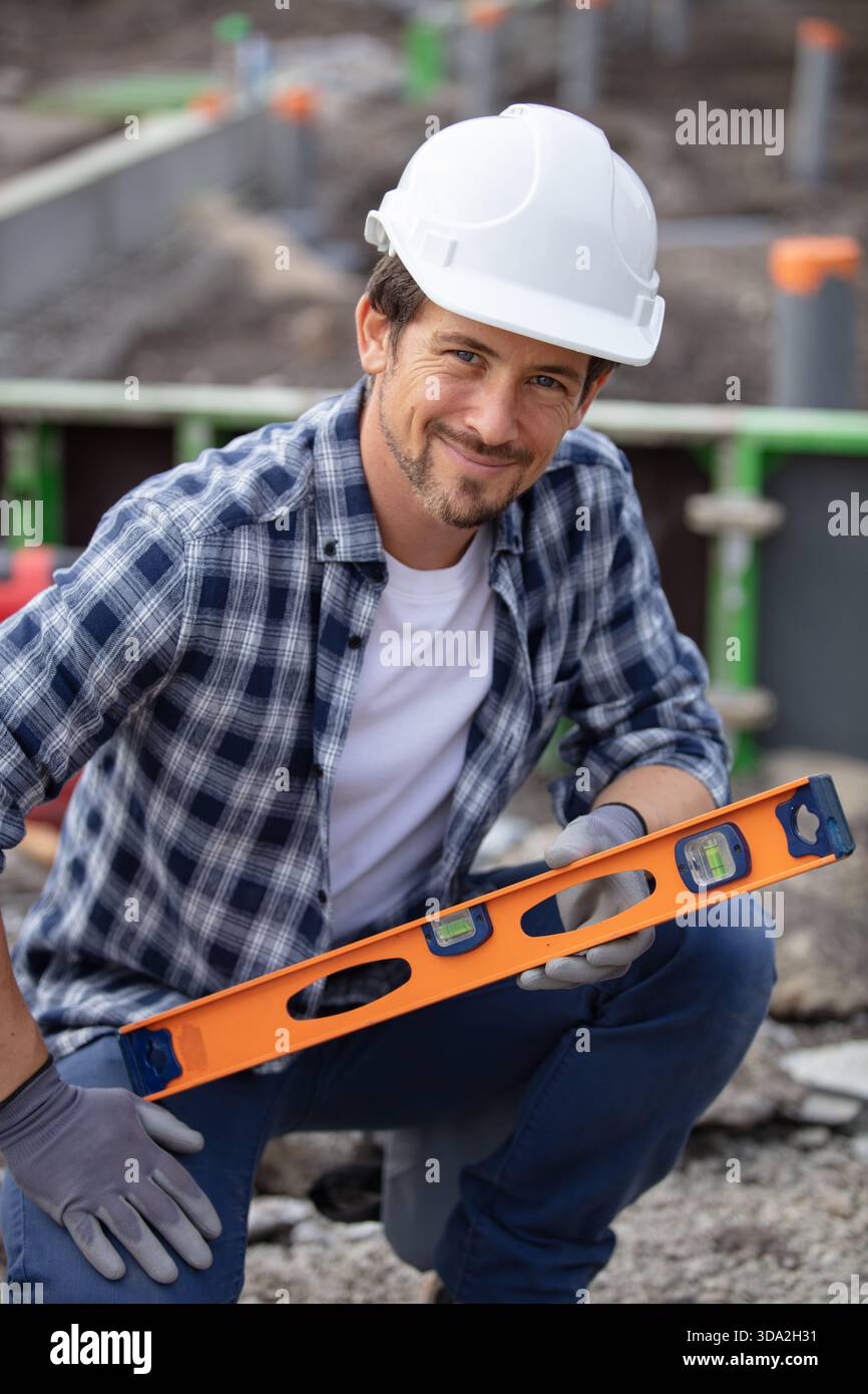 young handyman using spirit level outdoors Stock Photo