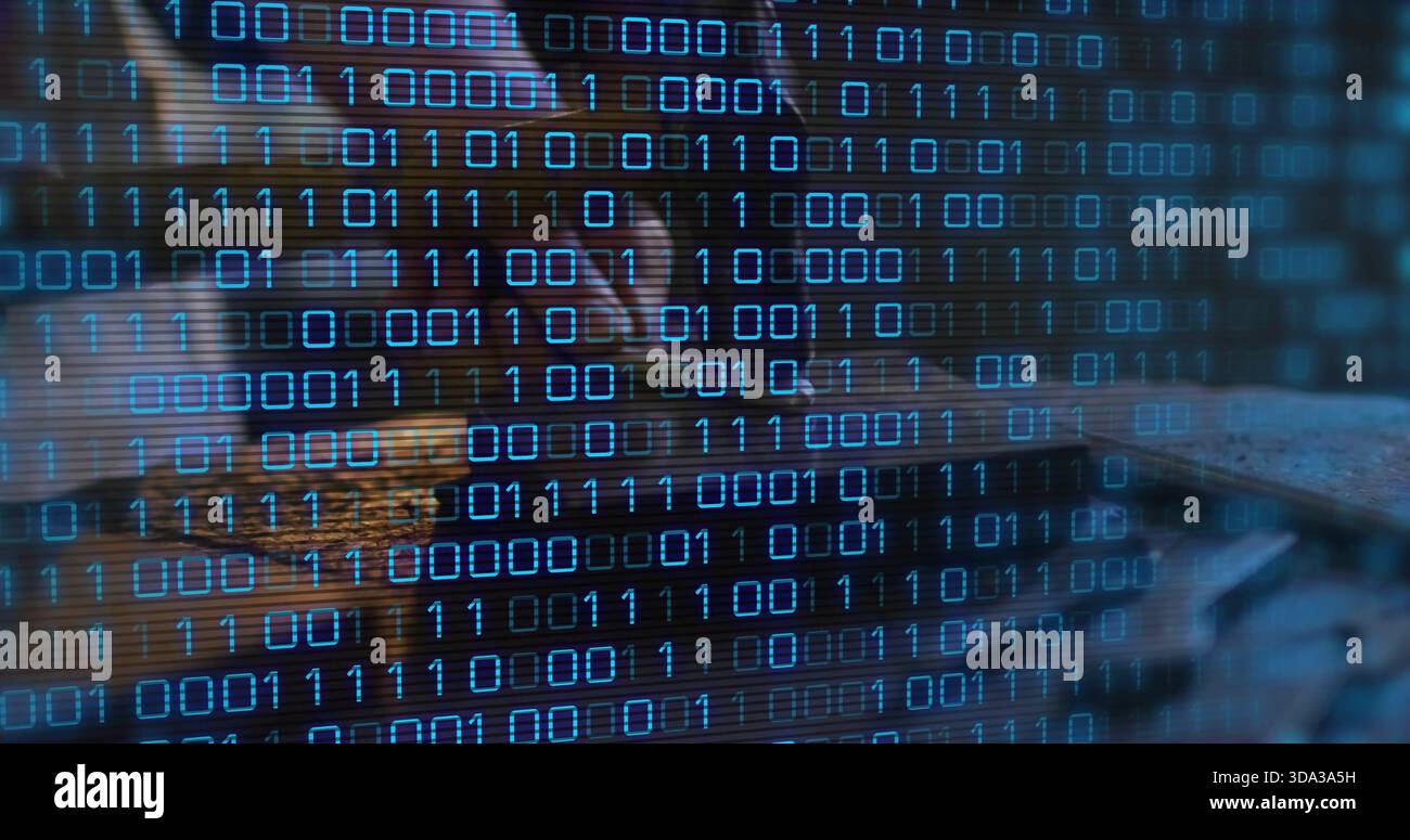 Leaning female analyst coding on laptop at dim desk, wearing dark top, glasses with binary code Stock Photo