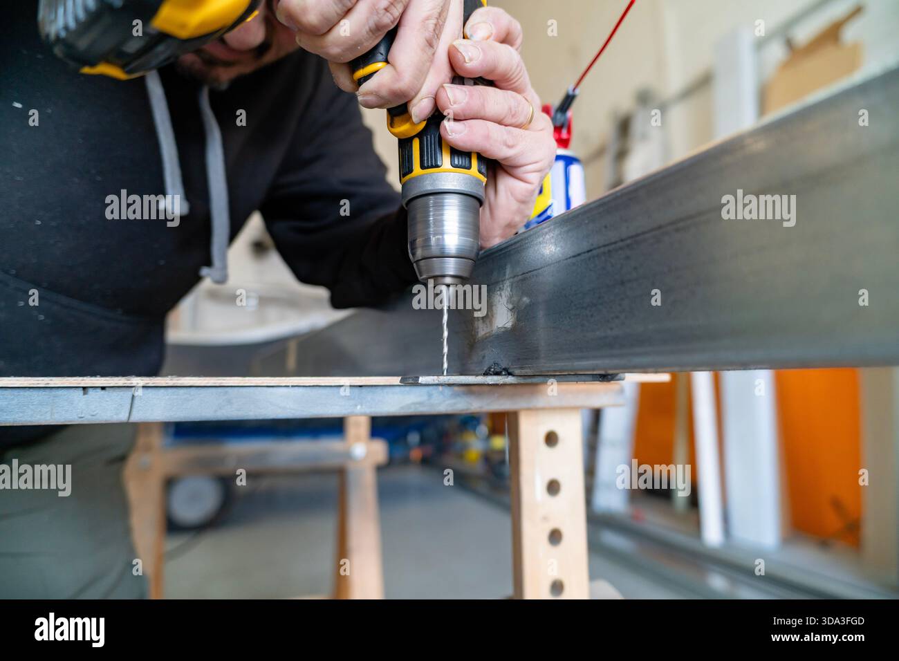 Man using power tool drilling metal bar in a workshop Stock Photo