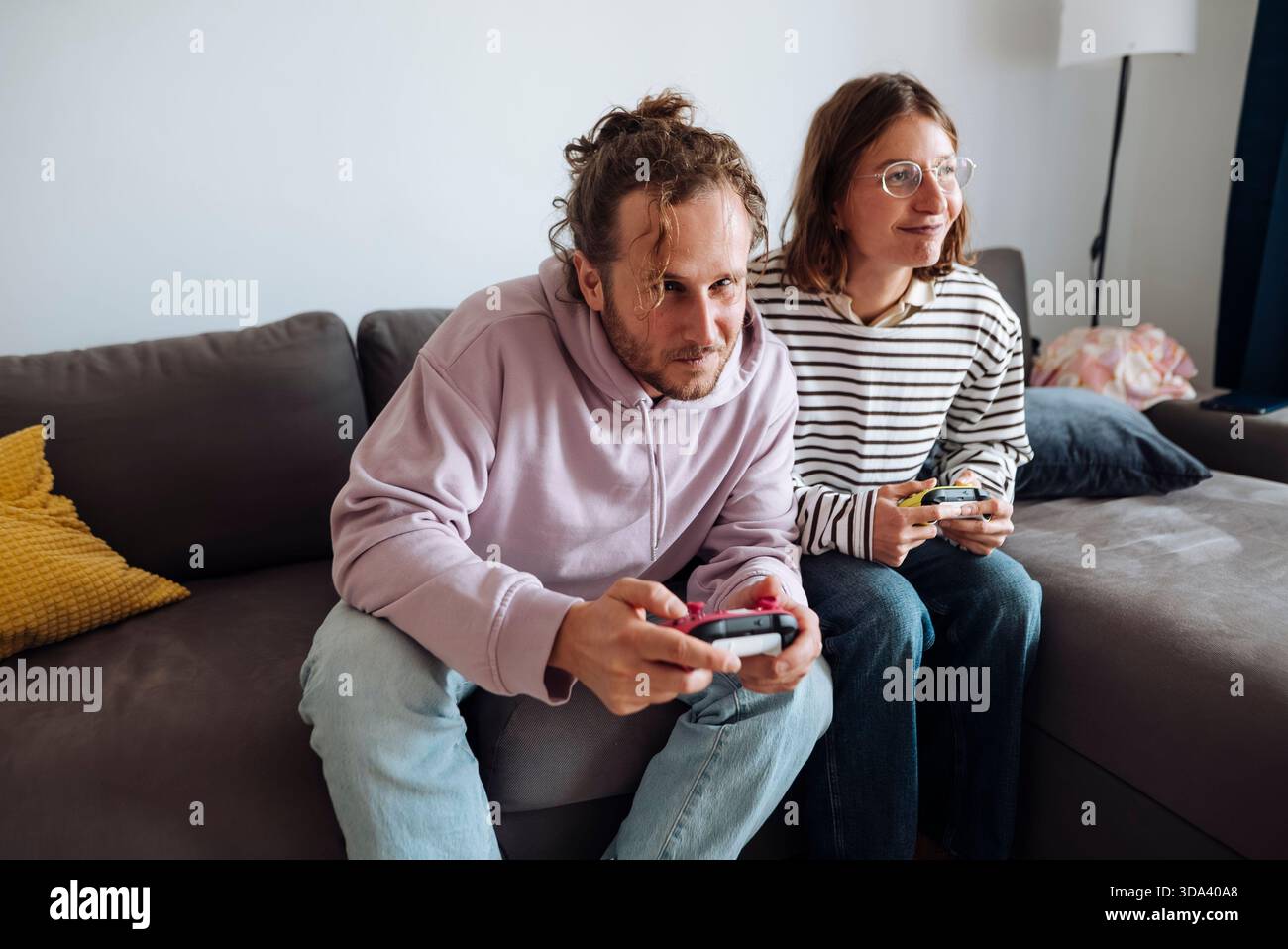 Pair of grownups intensely competing in console games at home Stock Photo