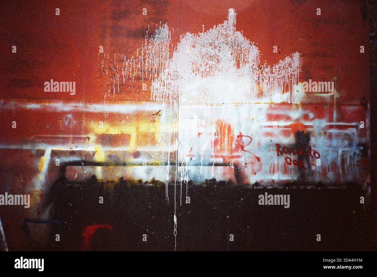 Analog flash shot of a red workshop wall with spray paint marks, creating an abstract textured composition, captured on Olympus film camera. Stock Photo