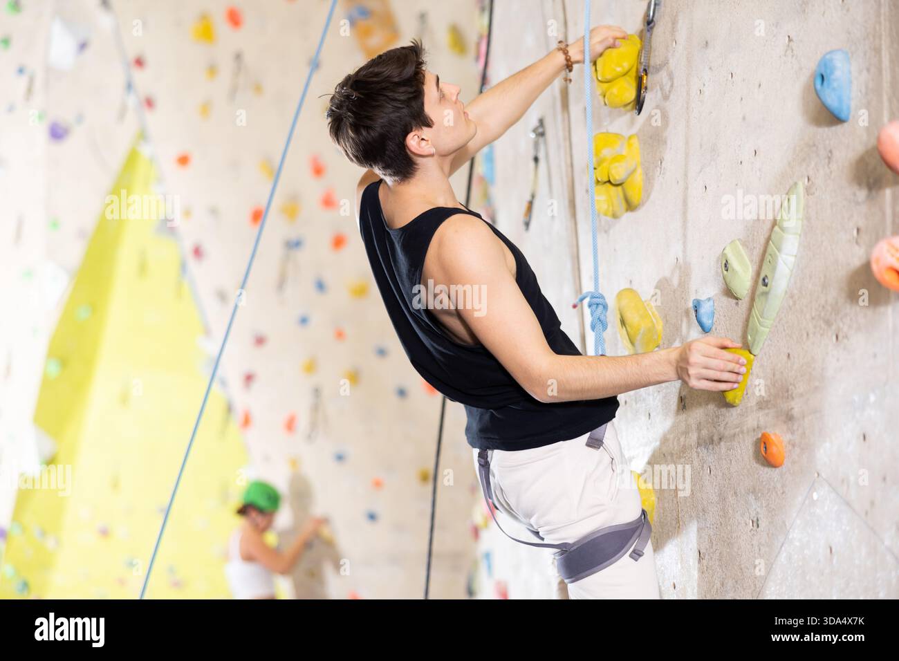 Determined young man doing his best at climbing artificial wall Stock Photo