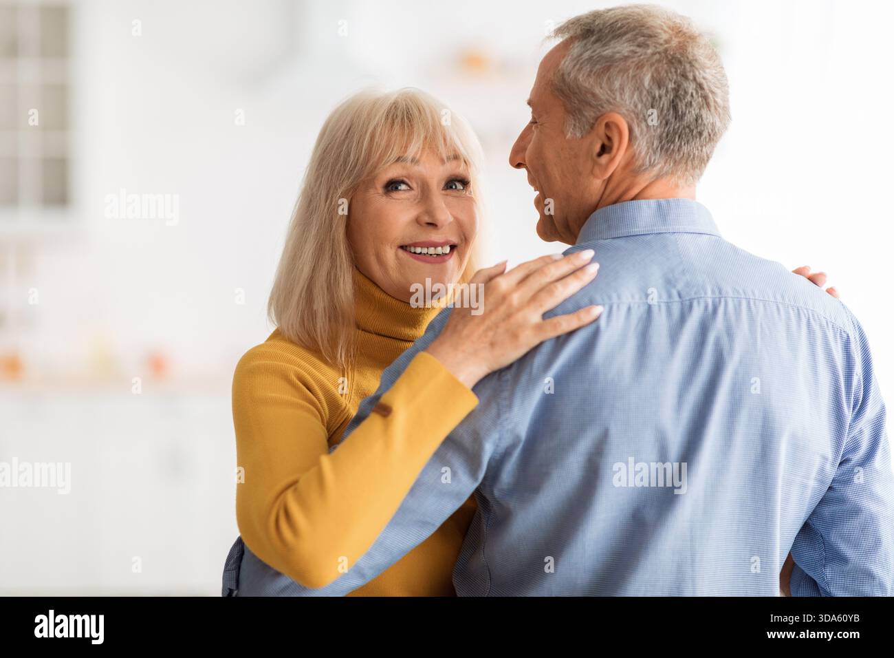 Senior Couple Sharing a Joyful Moment While Dancing in Their Bright Kitchen Stock Photo