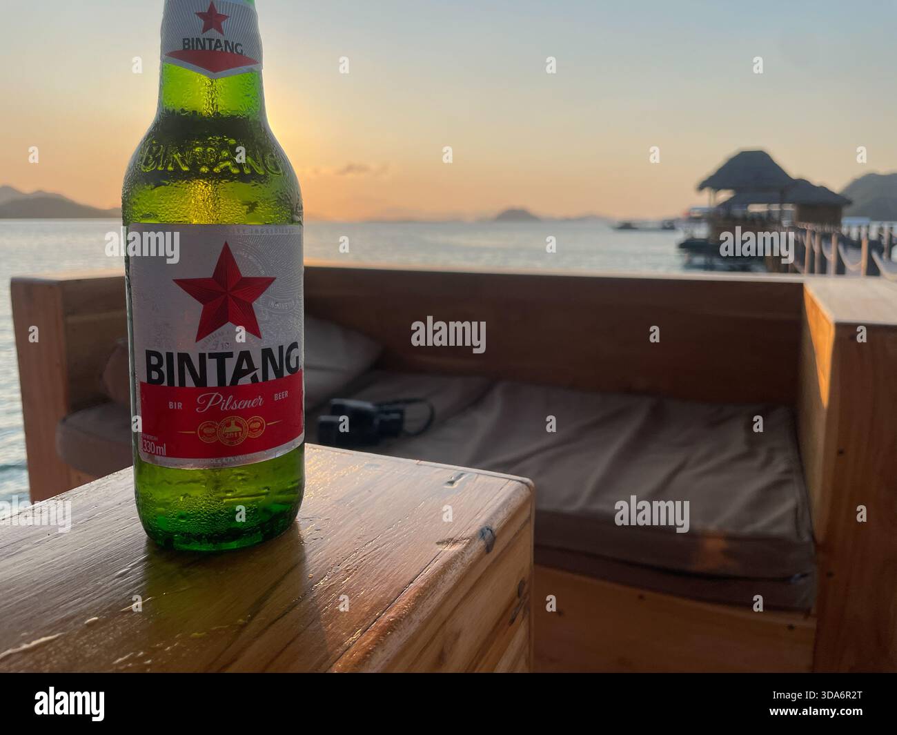 A bottle of Bintang beer on a table with the sunset in the background, Scuba Junkie Komodo, Flores Island, Indonesia - Smartphone Captured Stock Image
