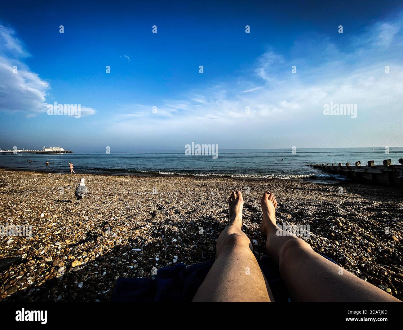 A POV of legs laying on Worthing beach on a summers afternoon - Smartphone Captured Stock Image