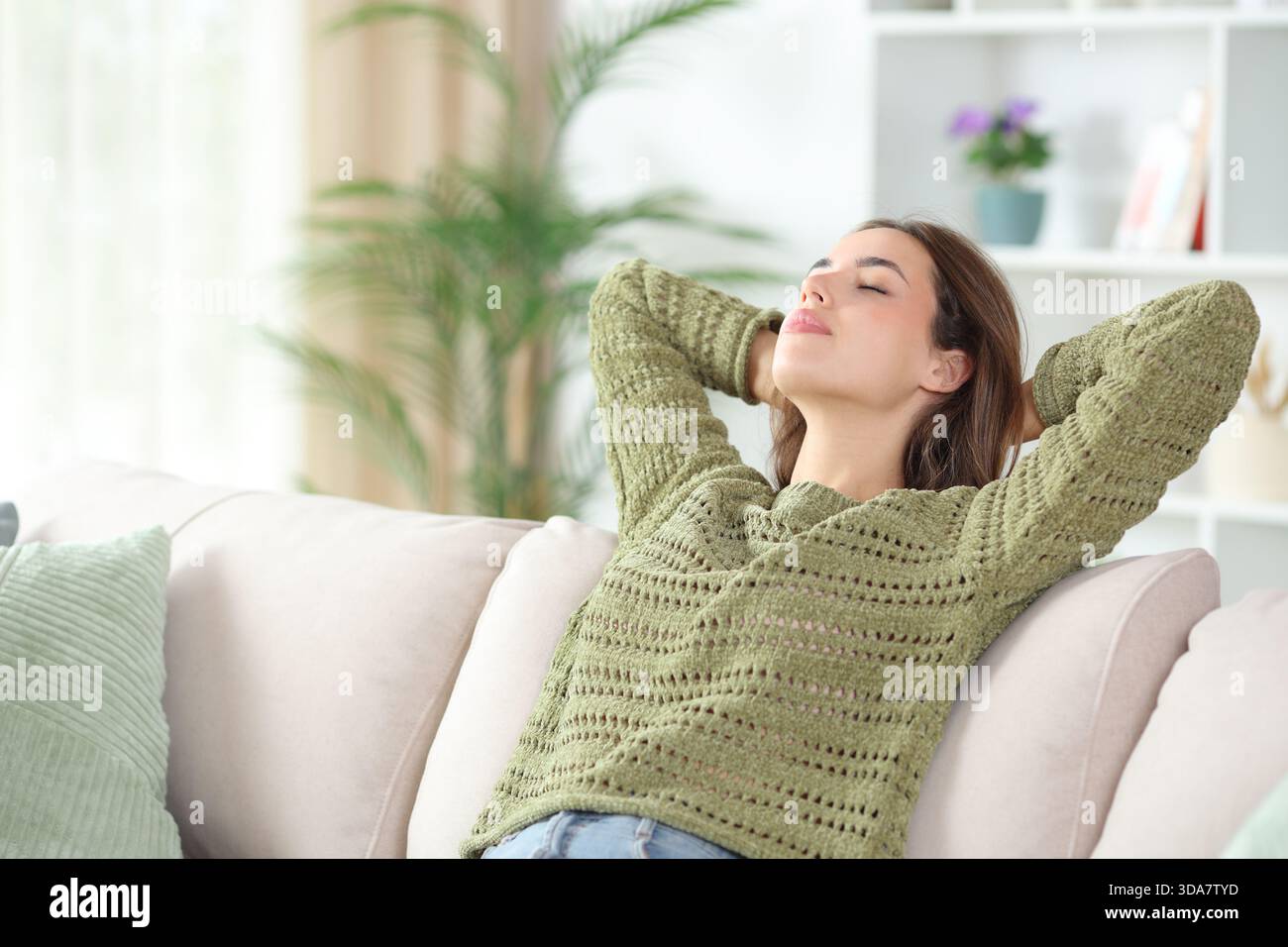 Relaxed woman in green resting sitting on a sofa at home Stock Photo