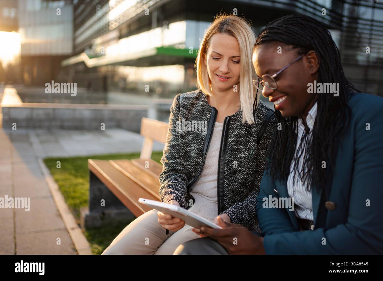 Diverse businesswomen collaborating outdoors using digital tablet Stock Photo