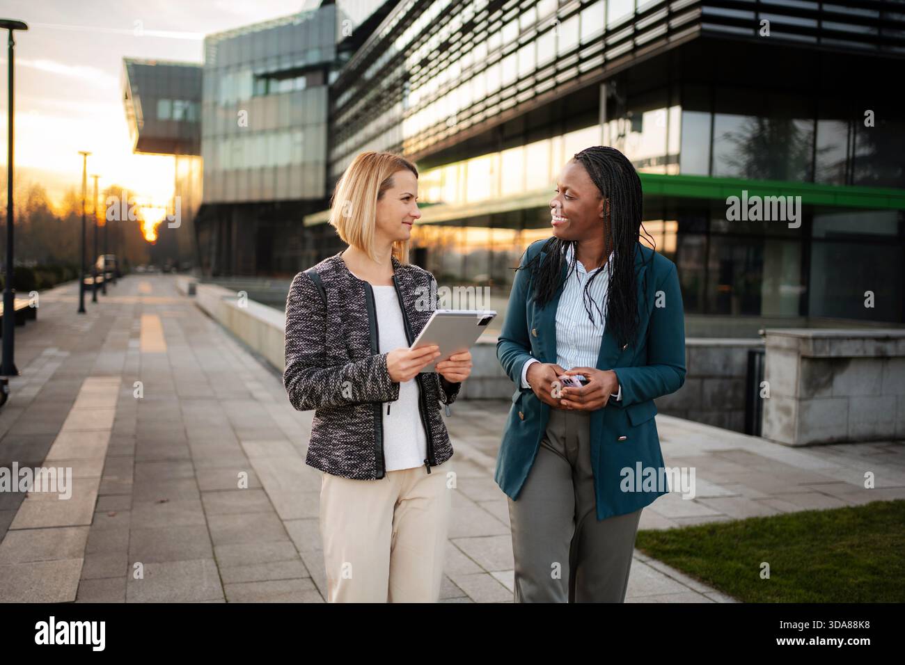 Diverse businesswomen walking and collaborating using digital tablet Stock Photo