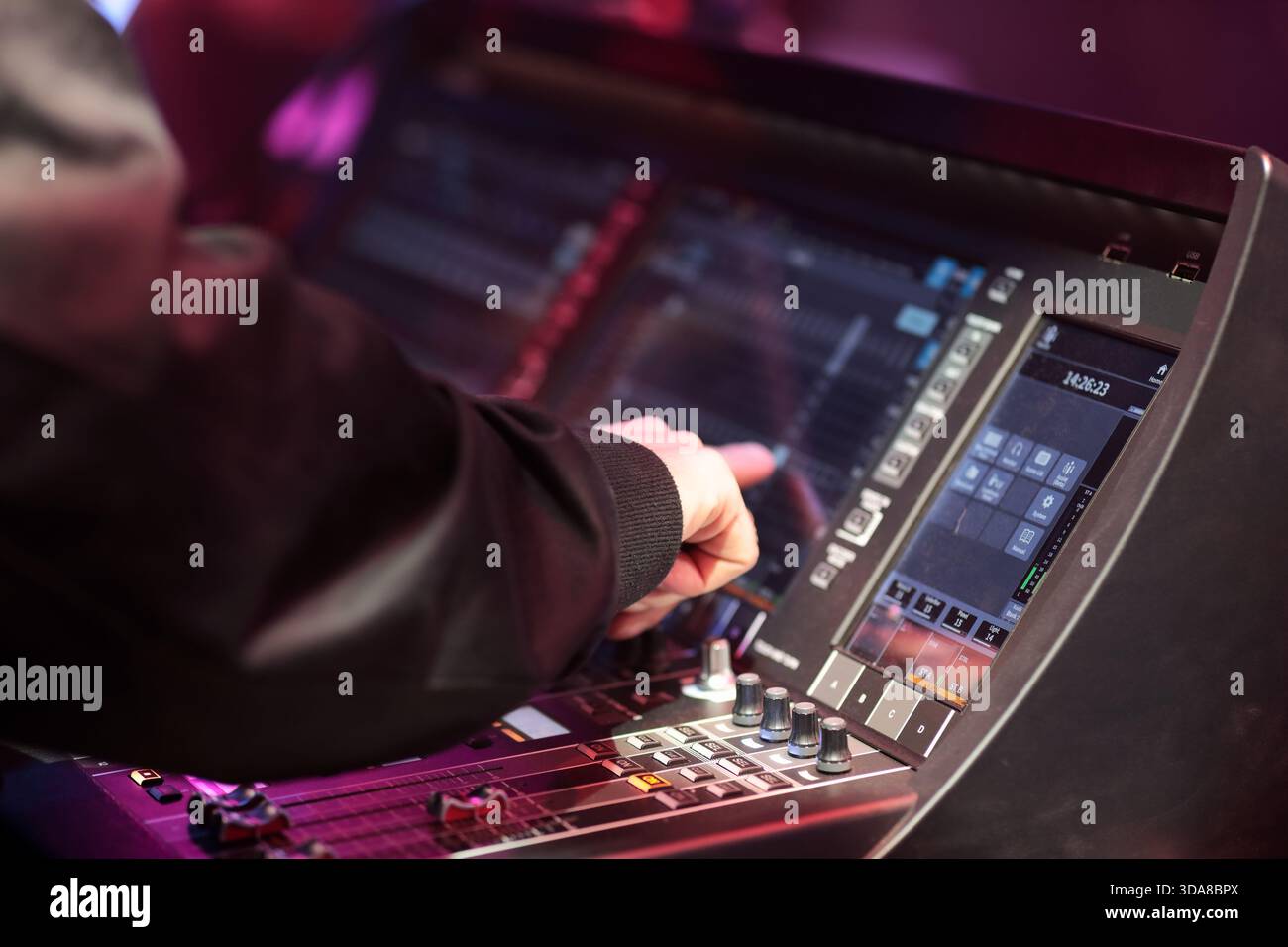Sound board operator controls digital mixing console during live event. Selective focus. Stock Photo