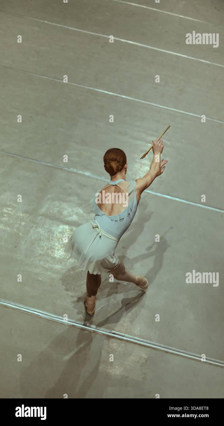 Ballet dancer preparing movement with baton prop on studio floor Stock ...