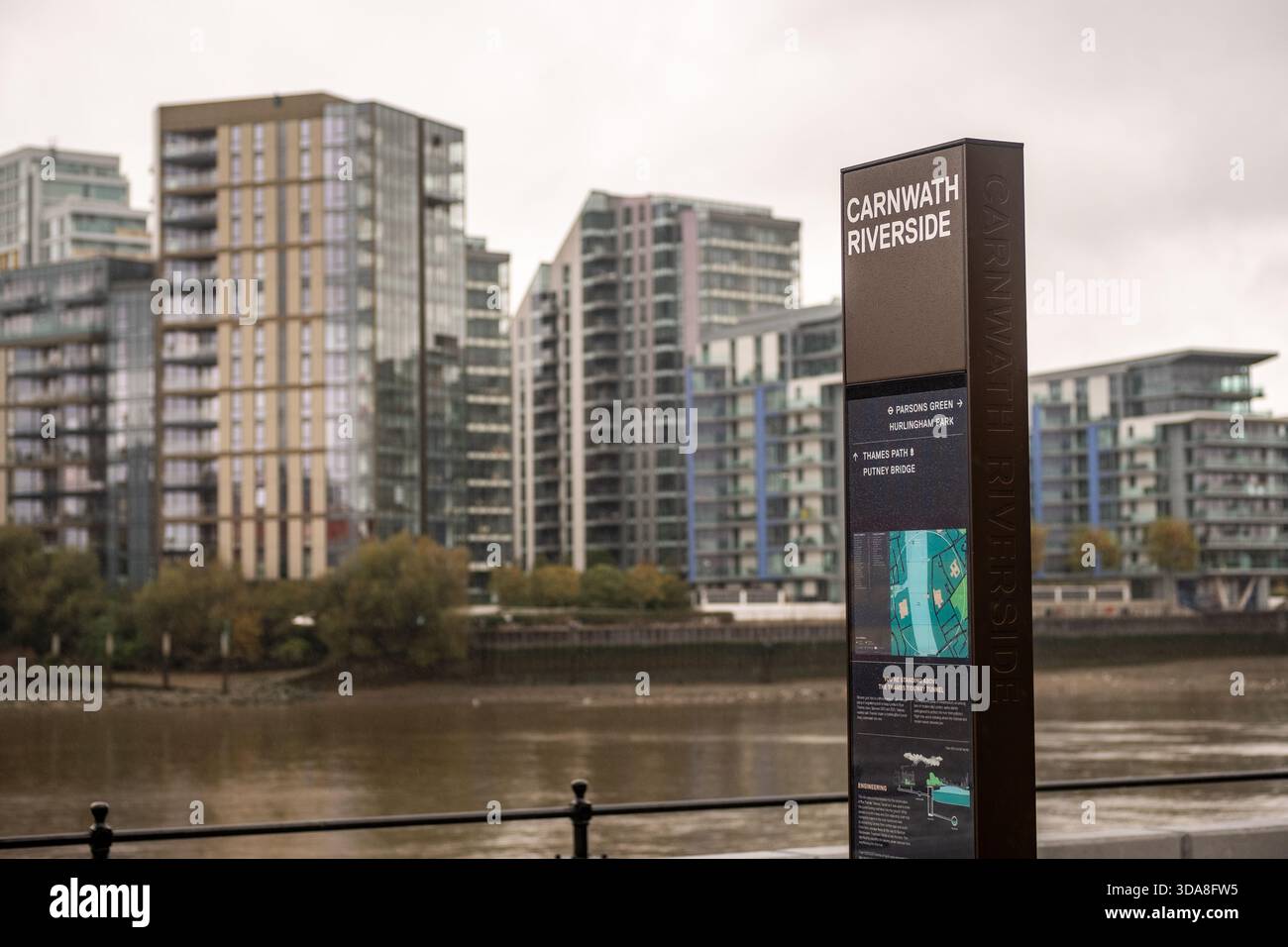 LONDON - NOVEMBER 7, 2025: Carnwath Riverside Thames Path Sign – Fulham Wayfinding with Riverside Quarter Towers Across River in Wandsworth Stock Photo