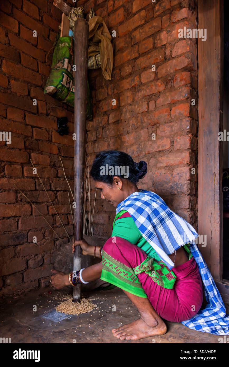 Woman during traditional rice milling with a mortar and pestle, Odisha, India Stock Photo
