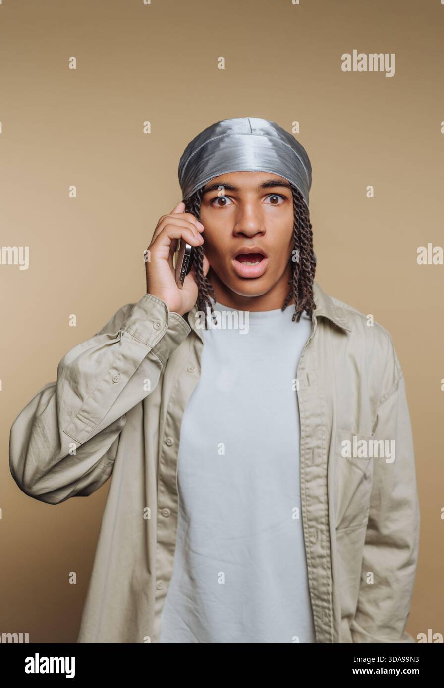 Young man with surprised expression talking on phone. Stock Photo