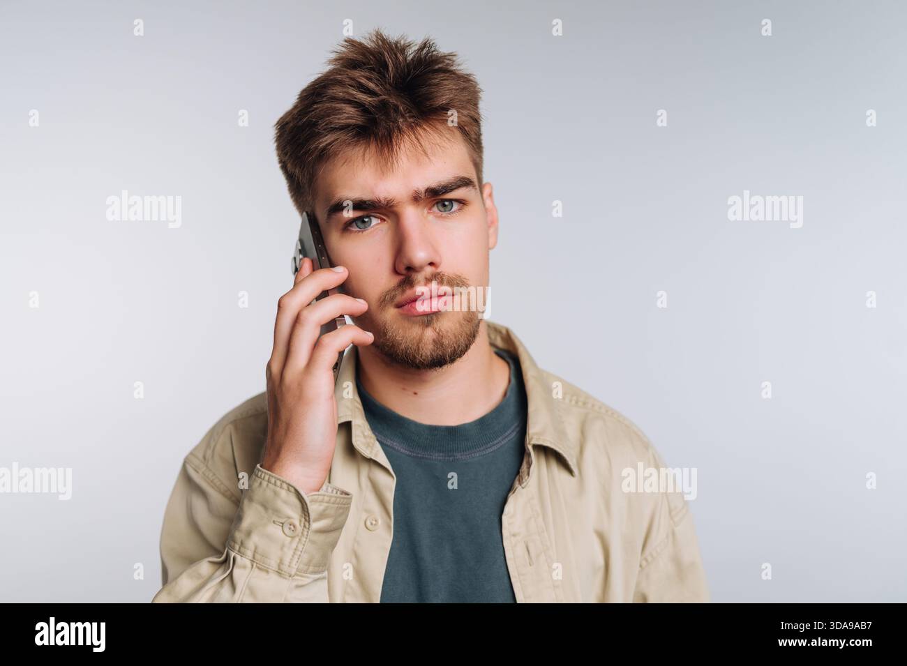 Young man with a serious expression talking on a smartphone. Stock Photo