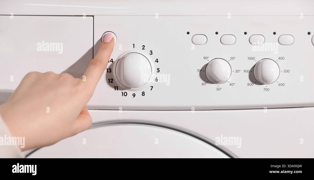 Woman pressing button on washing machine, closeup Stock Photo