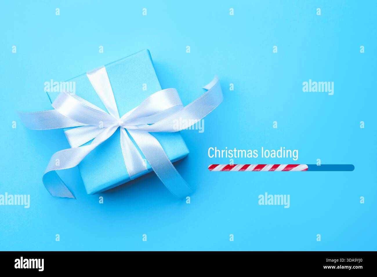 Christmas expectation. Candy cane as loading bar. Gift box on light blue background, top view Stock Photo