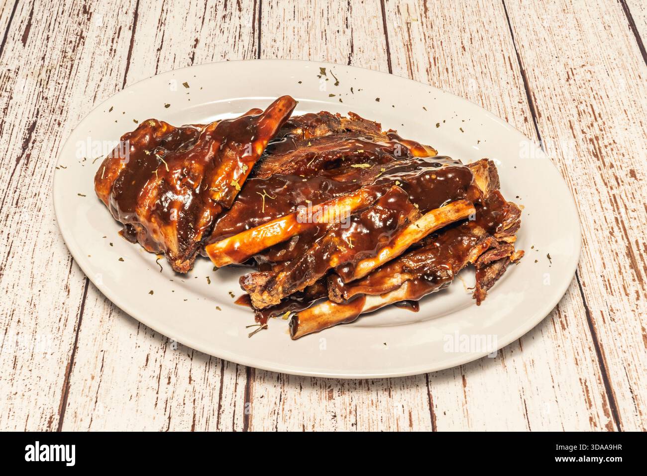 Barbecued pork ribs with a caramelized, sticky smoky BBQ sauce crust, served with grilled corn on the cob and coleslaw Stock Photo