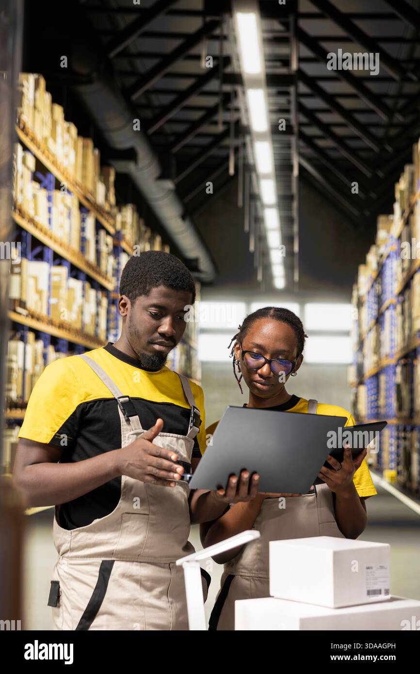 Black employees checking inventory and shipment details on laptop ...