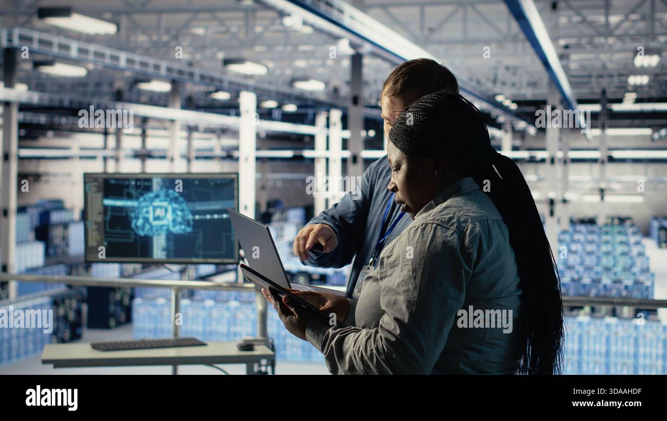 Technicians working together in server room, optimizing deep learning AI systems handling tasks. Data center coworkers doing brainstorming to adjust artificial intelligence model parameters, camera B Stock Photo