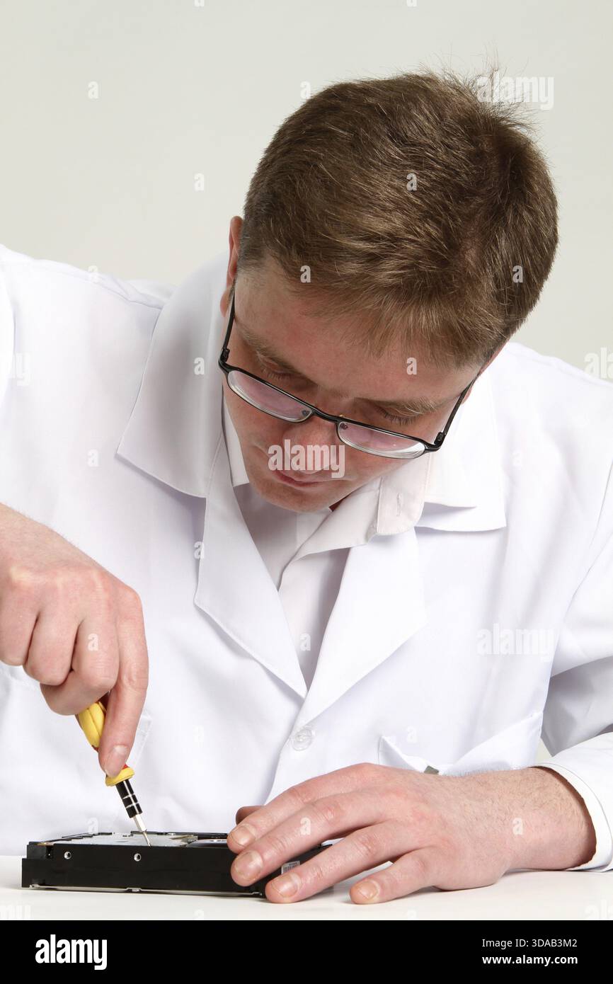 A man with a screwdriver disassembles a computer hard drive repair Stock Photo