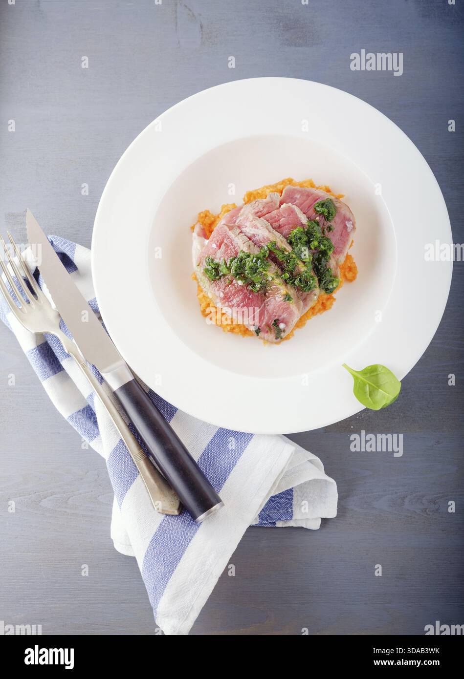 A plate of sliced roast beef, pumpkin and salsa verde Stock Photo