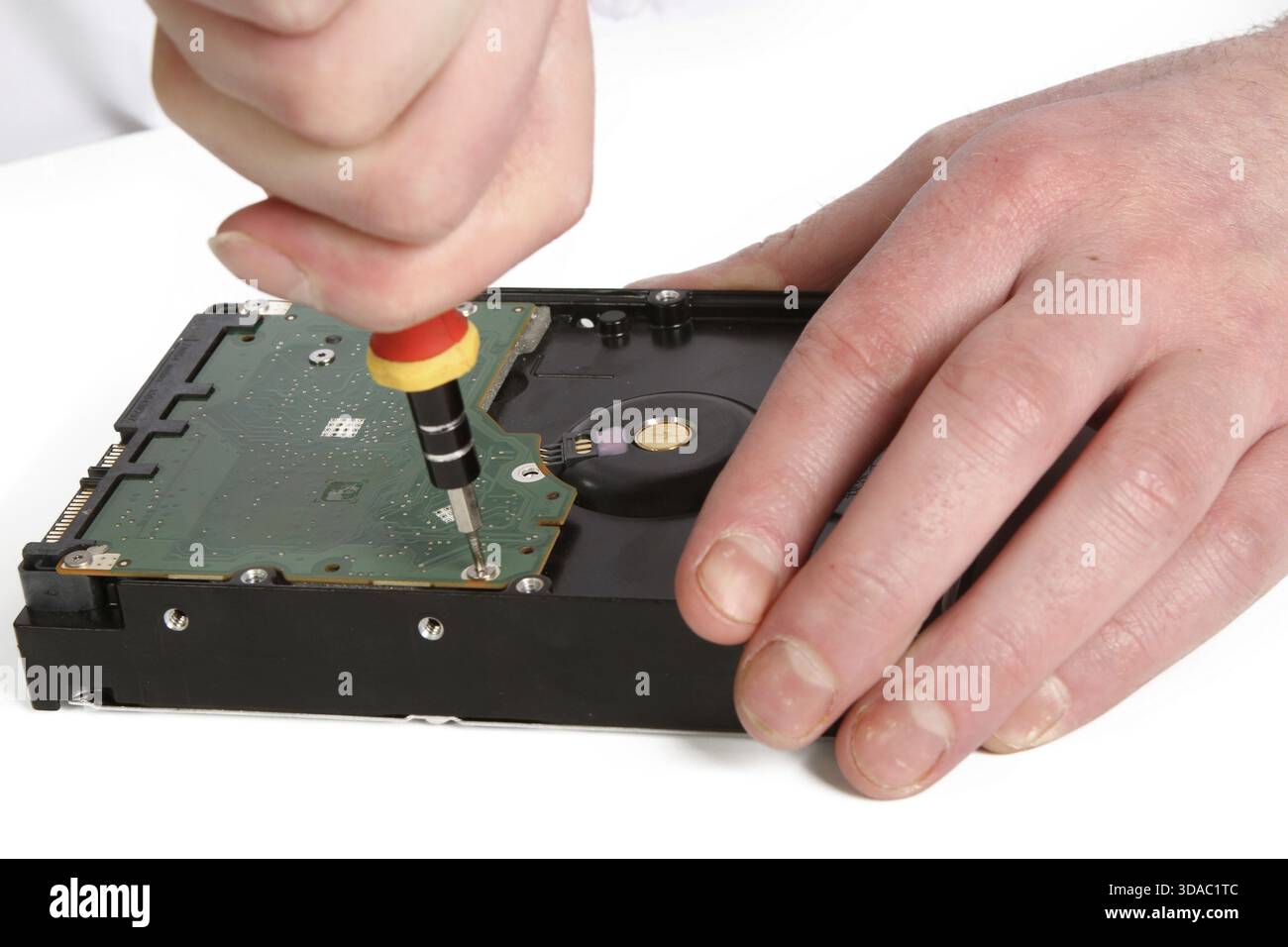 A man with a screwdriver disassembles a computer hard drive repair Stock Photo